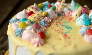 Kolorowy tort z kremem, bezą, cukierkami i posypką.