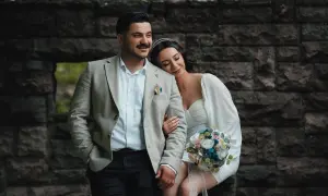 Para młoda w stylizacjach ślubnych na tle kamiennej ściany.