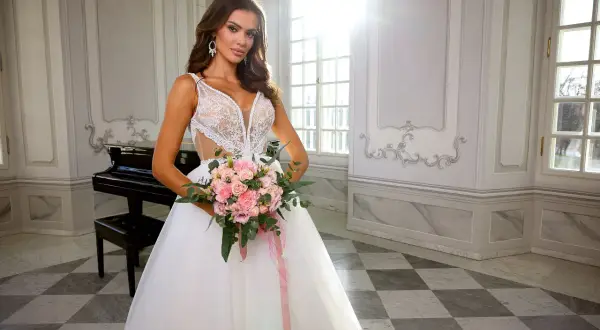Panna młoda w sukni ślubnej z bukietem różowych kwiatów, w eleganckim wnętrzu z fortepianem.