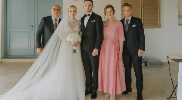Para weselna z rodzicami. Panna młoda w sukni z welonem, pan młody w garniturze. Obok nich mama weselna w różowej sukience i ojcowie.