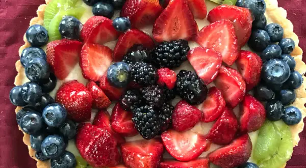 Kolorowa tarta z owocami: truskawki, borówki, jeżyny i kiwi.