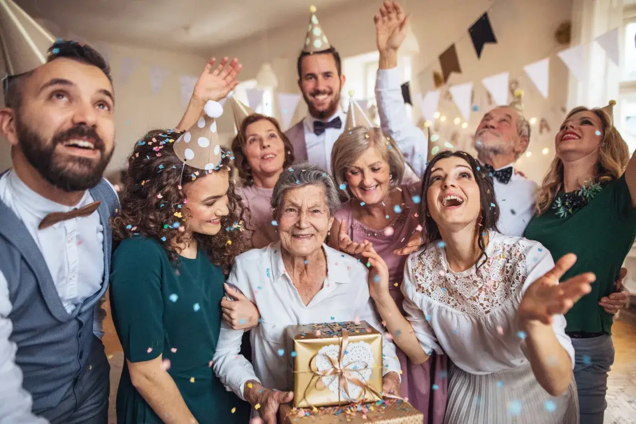Rodzina świętuje 50-lecie ślubu. Wszyscy w eleganckich strojach, z konfetti i w czapkach urodzinowych. Idealny pomysł, jak się ubrać na 50 lecie ślubu!