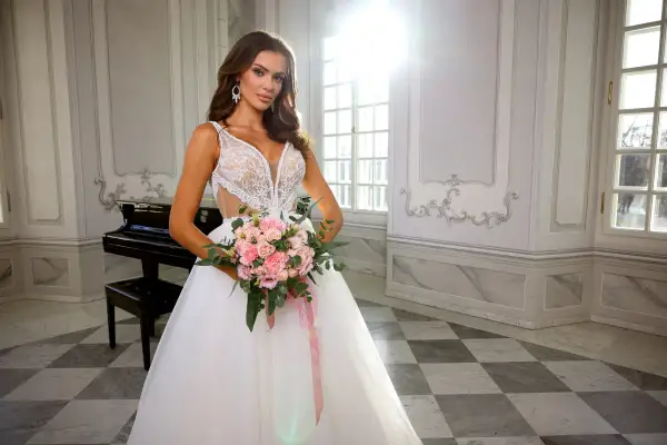Panna młoda w sukni ślubnej z bukietem różowych kwiatów, w eleganckim wnętrzu z fortepianem.
